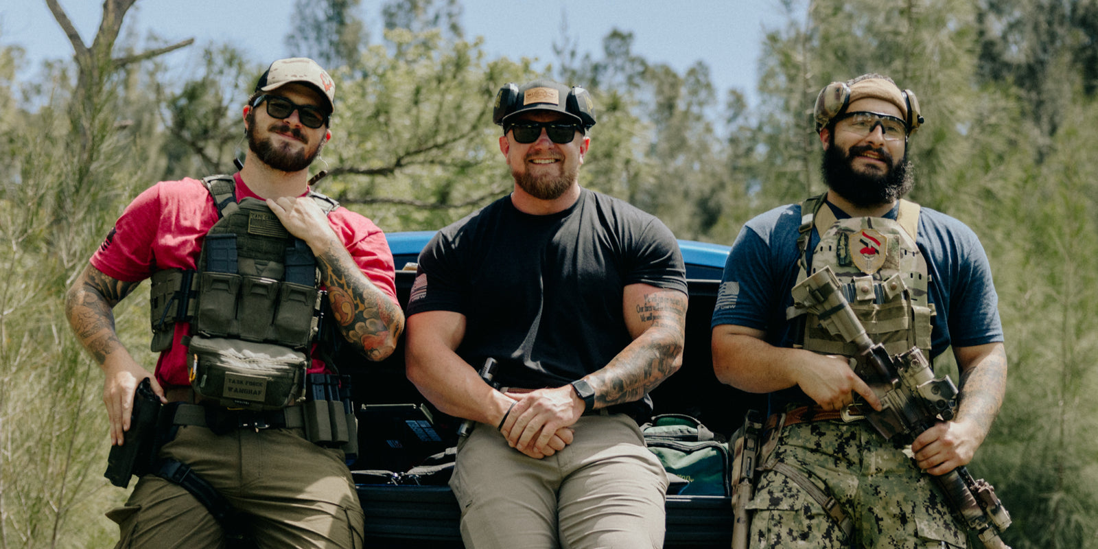 Three men sitting on a truck tailgate outdoors